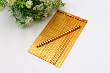 Porta blocos em prata dourada com bandas relevadas ao alto e lapiseira acoplada.